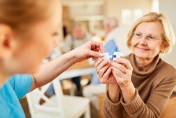 Eine ältere Frau fügt mit Hilfe einer Betreuerin zwei Puzzle-Teile zusammen | © Robert Kneschke - stock.adobe.com